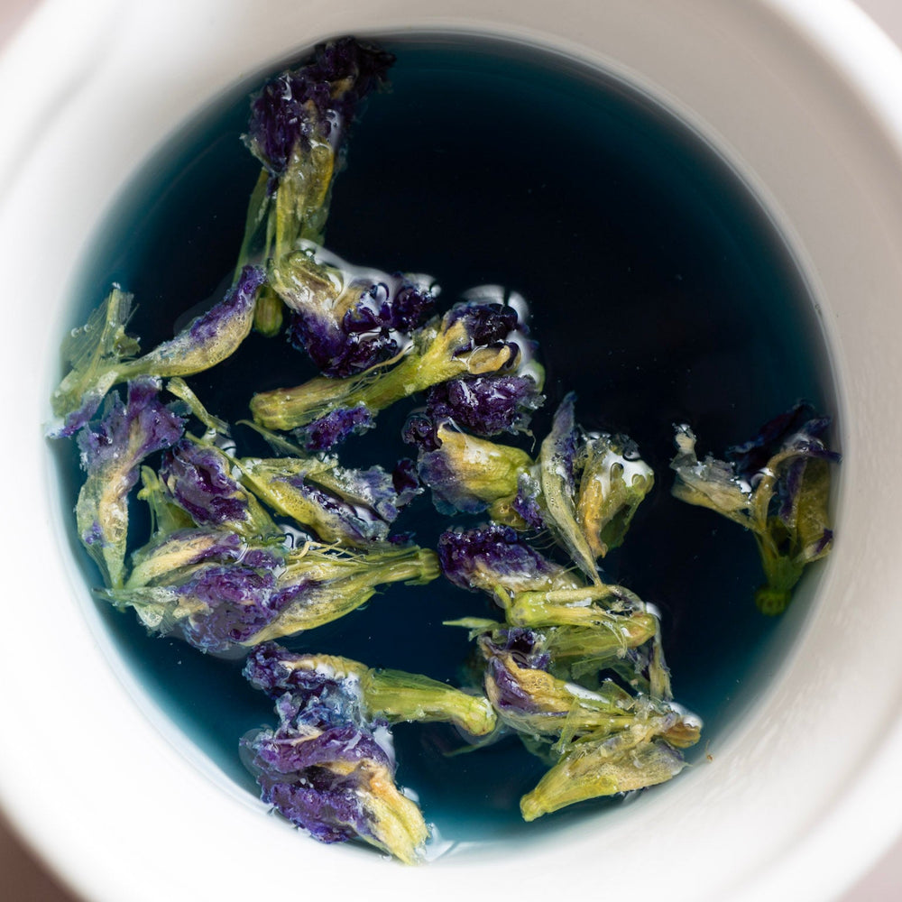Cup of Butterfly Pea tea turning purple with a squeeze of lime