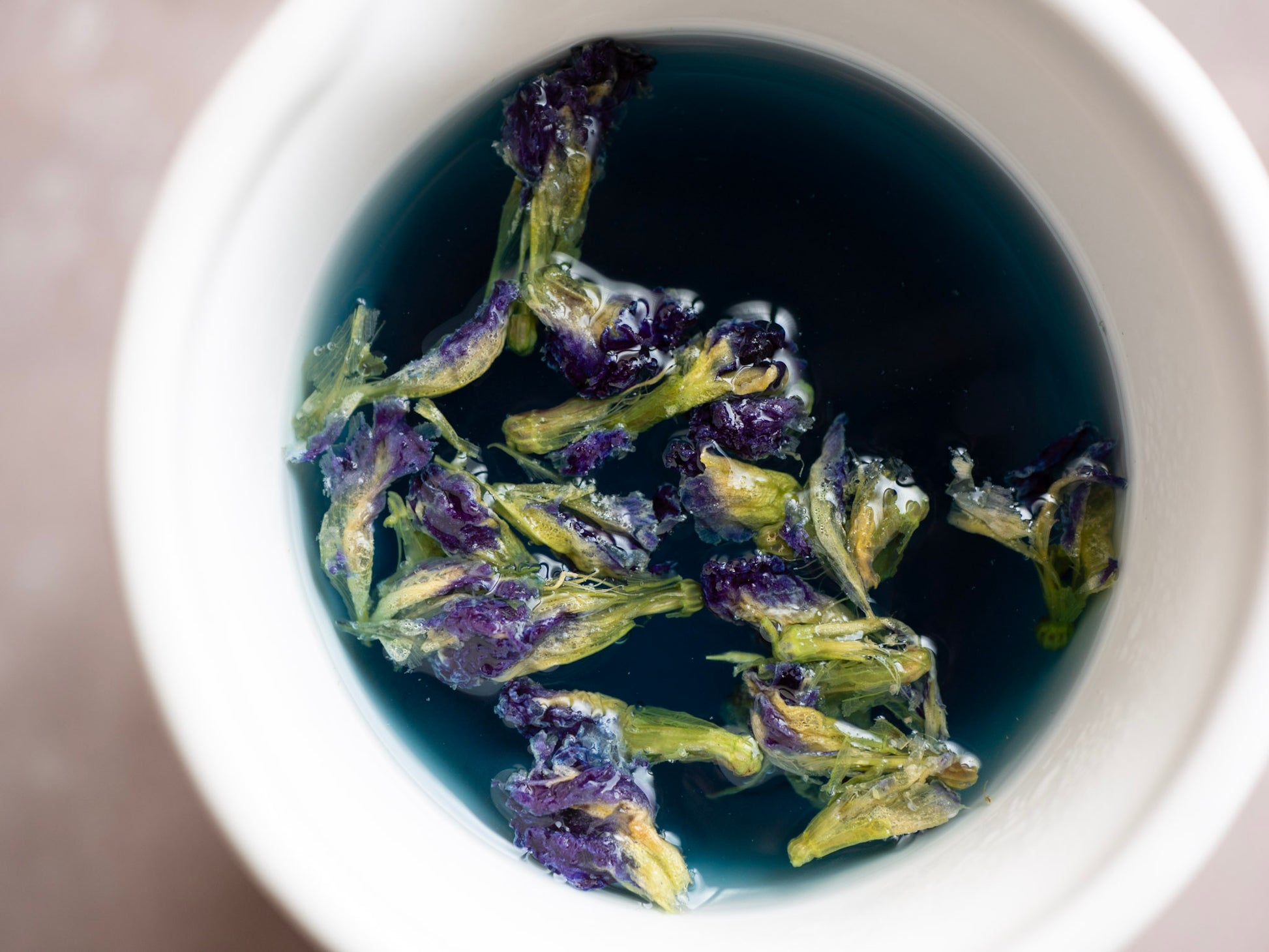 Cup of Butterfly Pea tea turning purple with a squeeze of lime